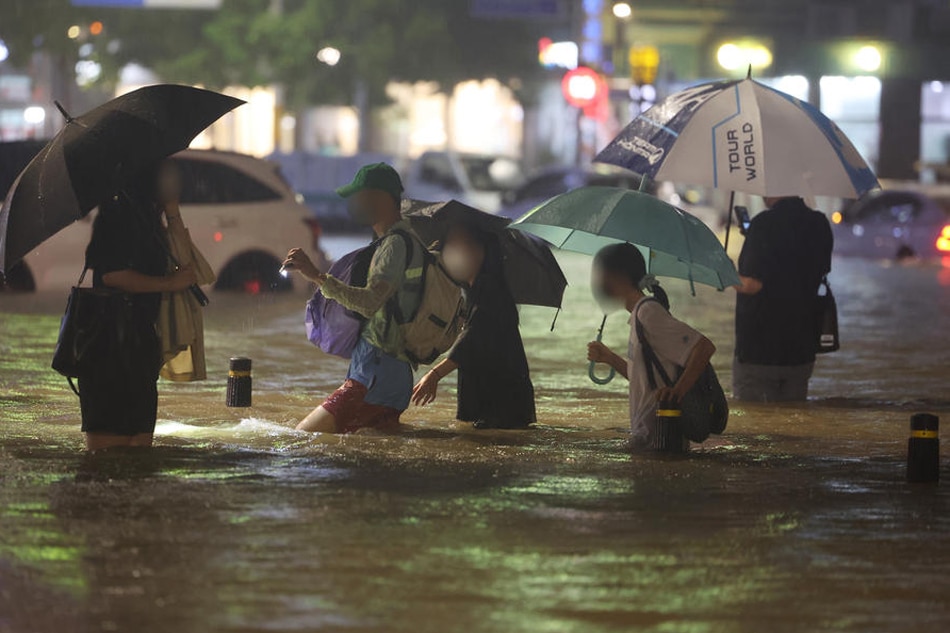 People wade though an inundated road in southern Seoul, South Korea, Aug. 8, 2022, as heavy rainfall of over 100 millimeters per hour, the heaviest in 80 years, battered Seoul and surrounding areas. Yonhap/EPA-EFE