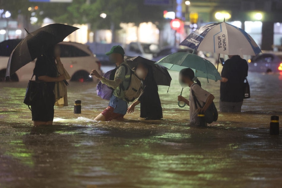 People wade though an inundated road in southern Seoul, August 8, 2022, as heavy rainfall of more than 100 millimeters per hour, the heaviest in 80 years, battered Seoul and surrounding areas. Yonhap South Korea Out, EPA-EFE