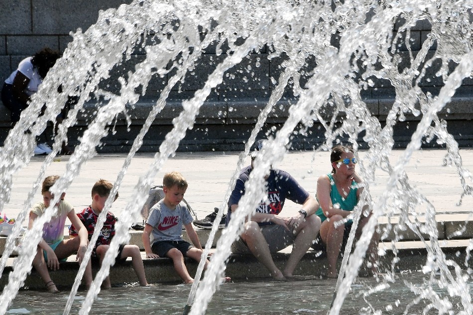 People put their feet in the water at the National World War II Memorial on the National Mall in Washington, DC, Aug. 12, 2021, as a heat wave continues in the area. Olivier Douliery, AFP/File