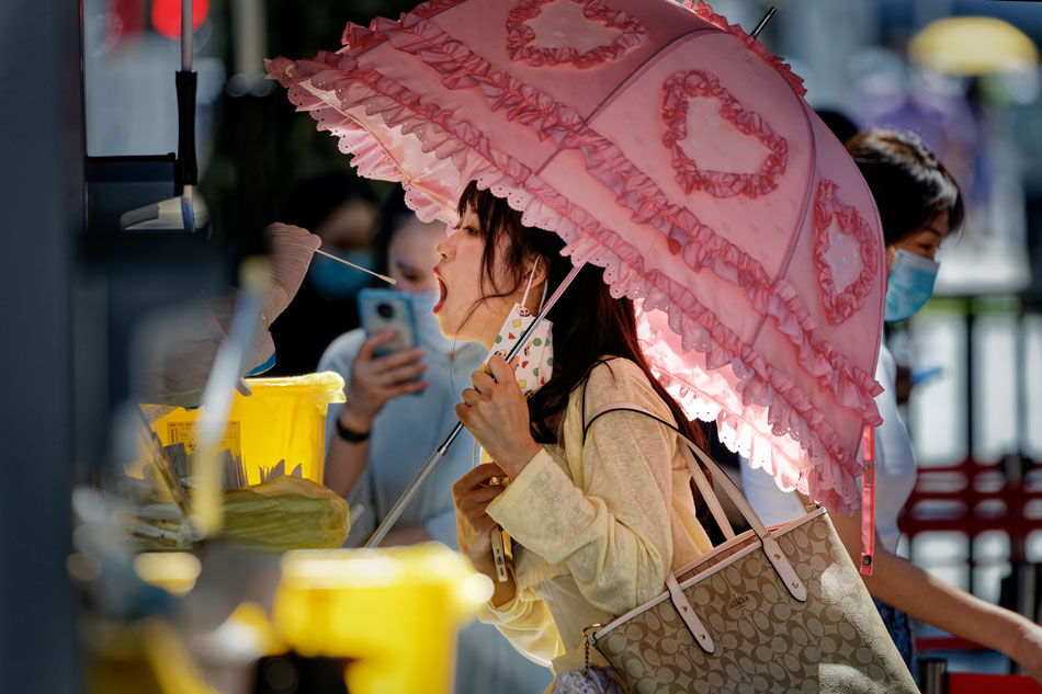 A woman takes an RT-PCR test on the street, in Shanghai, China on Aug. 4, 2022. Shanghai continues PCR mass testing to control community transmission of COVID-19. Alex Plavevski, EPA-EFE