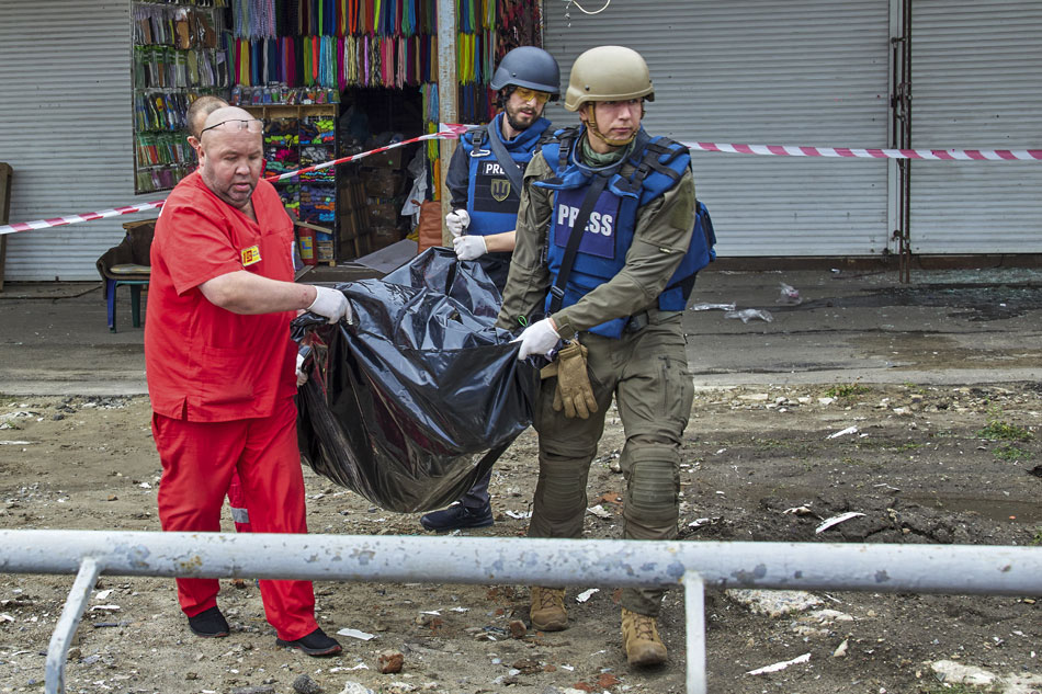 Medical workers and journalists carry the body of a victim following a Russian rocket strike hitting a bus stop near a market in Kharkiv, Ukraine, July 21, 2022. At least three people were killed and 23 injured in the attack, according to the Kharkiv