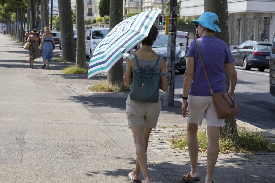 A woman carrying an umbrella to protect herself from the sun walks with another woman at the bank of the Geneva lake during a heatwave in Geneva, Switzerland, 25 July 2022, with temperatures reaching 36 degrees Celsius. EPA-EFE/SALVATORE DI NOLFI
