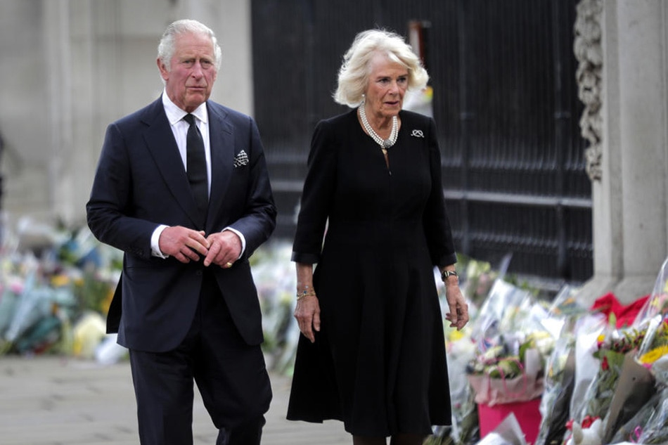 King Charles III and Camilla, the Queen Consort, look at the floral tributes left outside Buckingham Palace in London, Sept. 9, 2022. Olivier Hoslet, EPA-EFE
