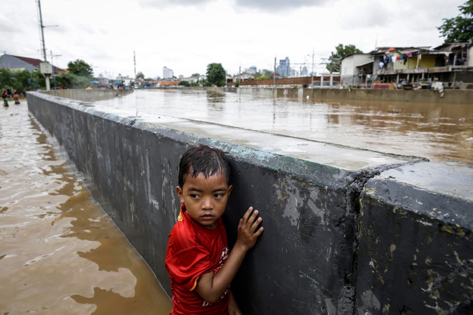 A boy stands next to a wall at a flooded road in Jakarta, January 2, 2020. Mast Irham, EPA-EFE