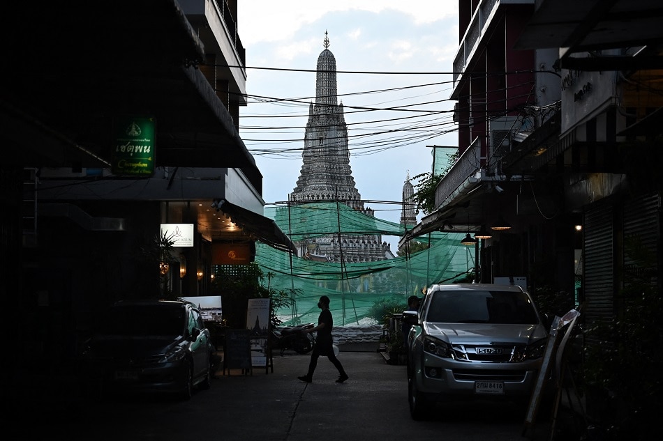 This photo taken on October 25, 2021 shows restaurant staff walking through an alley across from Wat Arun Buddhist temple in Bangkok. Lillian Suwanrumpha, AFP/file