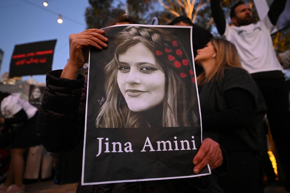 A protester holds a placard picturing Masha Amini during a demonstration in Melbourne, Sept. 29, 2022, following Amini's death in Iran. James Ross, EPA-EFE/File