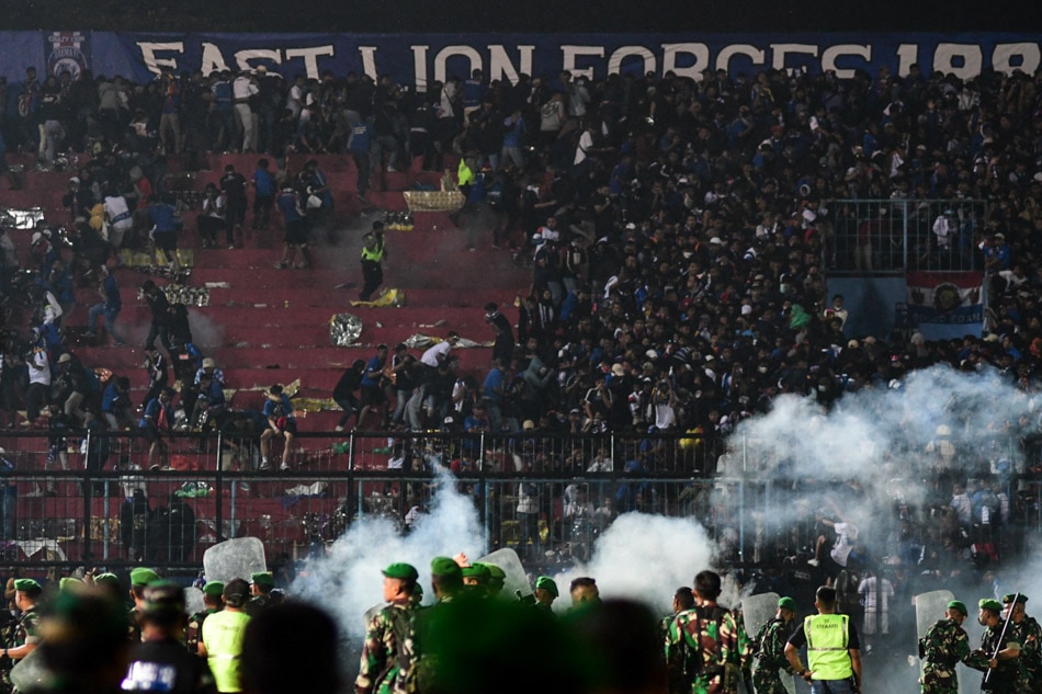 This picture taken on October 1, 2022 shows security personnel (lower) on the pitch after a clash ensued during a football match between Arema FC and Persebaya Surabaya at Kanjuruhan stadium in Malang, East Java, Indonesia. AFP