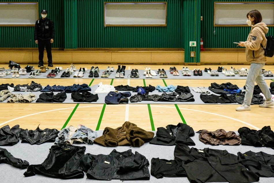 A journalist (R) walks amongst personal belongings retrieved by police from the scene of a fatal Halloween crowd surge that killed more than 150 people in the Itaewon district are displayed at a gymnasium for relatives of victims to collect, in Seoul on Nov. 1, 2022. At least 156 mostly young people were killed, and scores more injured, in a deadly crowd surge late October 29 at the first post-pandemic Halloween party in Seoul's popular Itaewon nightlife district. Anthony Wallace, AFP 