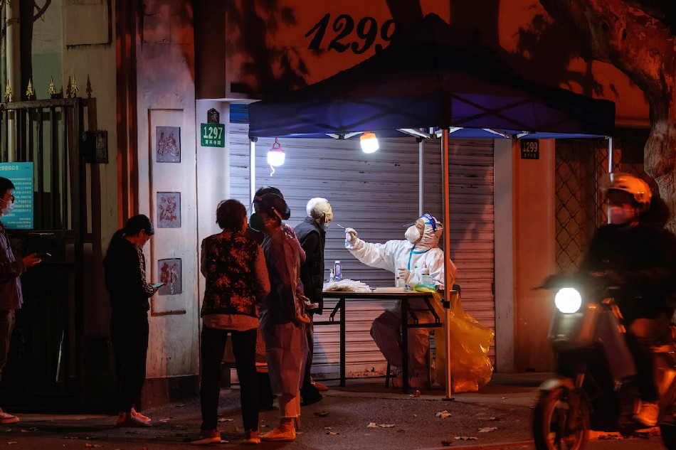 A woman undergoes a Coronavirus PCR test on the street in Shanghai, China, Nov. 3, 2022. Alex Plavevski, EPA-EFE