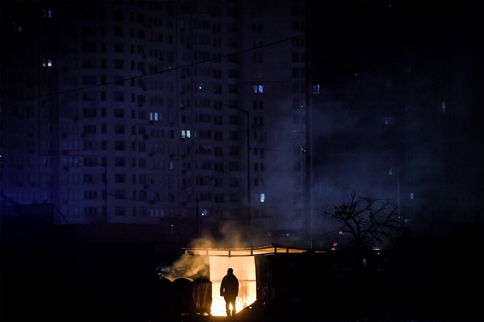 A man stands near burning garbage in front of an apartment building during a scheduled power cut in Kyiv (Kiev), Ukraine, on November 28, 2022. Oleg Petrasyuk, EPA-EFE