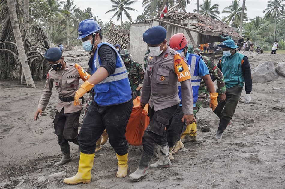 Rescuers carry the body of a victim at an area affected by the eruption of Mount Semeru in Lumajang regency, East Java, Indonesia, December 6, 2021. Ammar, EPA-EFE