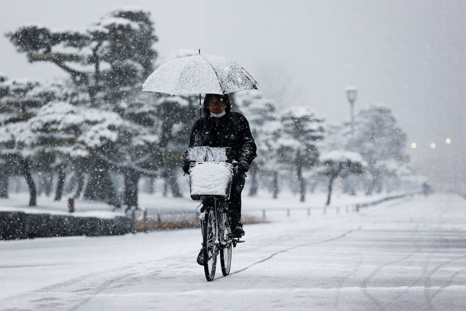 A man rides a bicycle in the snowfall amid the COVID-19 pandemic in Tokyo, Japan, Jan. 6, 2022. Issei Kato, Reuters