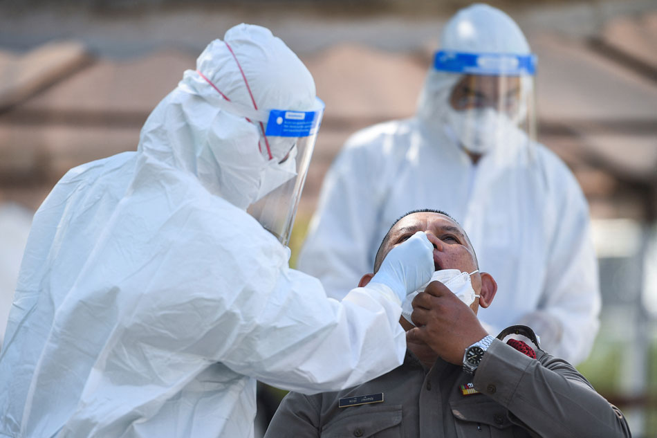  A health worker in personal protective equipment (PPE) takes a swab sample from a police officer for a rapid antigen test amid the coronavirus disease (COVID-19) outbreak, in Bangkok, Thailand, January 7, 2022. Chalinee Thirasupa, Reuters