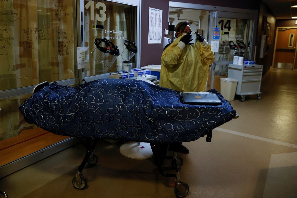 A funeral home worker puts on PPE gear before transporting the body of a deceased COVID-19 positive patient in Farmington, New Mexico, December 10, 2021. Shannon Stapleton, Reuters/file