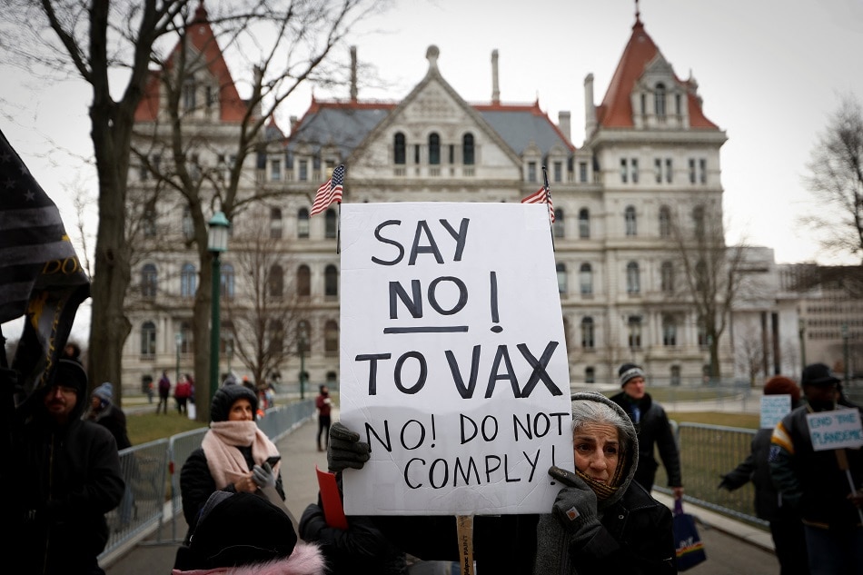 A protester holds a banner at a rally against mandates for the vaccines for the coronavirus disease outside the New York State Capitol in Albany, New York, on January 5, 2022. Mike Segar, Reuters
