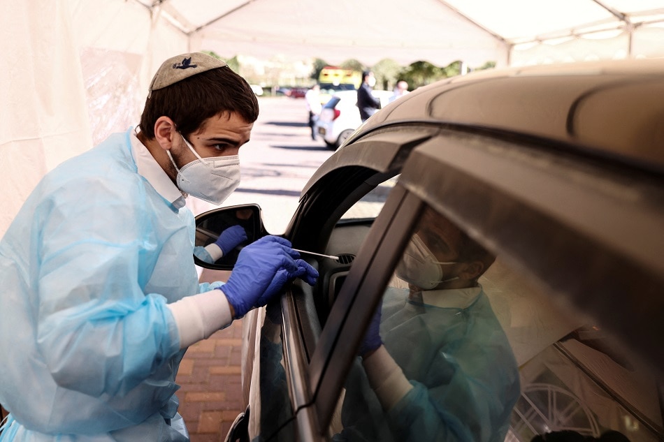 Medical staff carry out tests for COVID-19 at a drive-through site as Israel faces a surge in omicron variant infections, in Jerusalem, January 10, 2022. Ronen Zvulun, Reuters