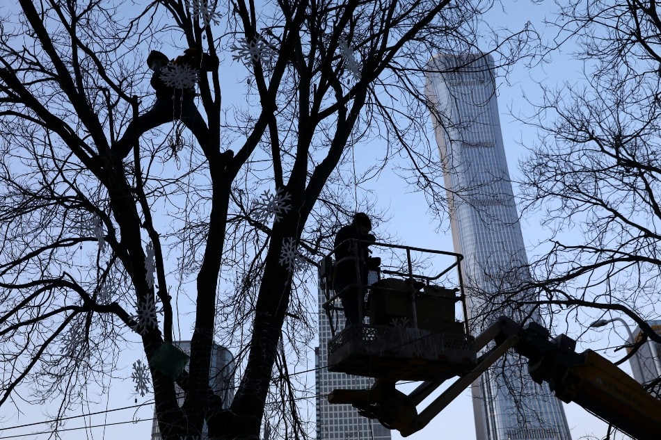 Workers hang decoration lights on a tree near the Central Business District (CBD) in Beijing, China January 16, 2022. Picture taken January 16, 2022. Tingshu Wang, Reuters