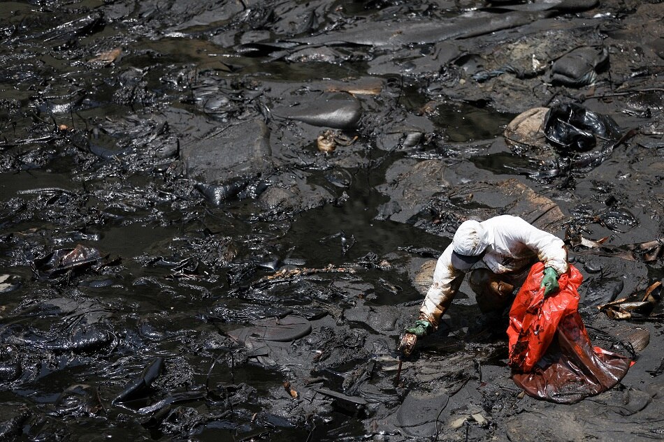 A worker cleans up an oil spill caused by abnormal waves, triggered by a massive underwater volcanic eruption half a world away in Tonga, at the Peruvian beach in Ventanilla, Peru, January 18, 2022. Pilar Olivares, Reuters