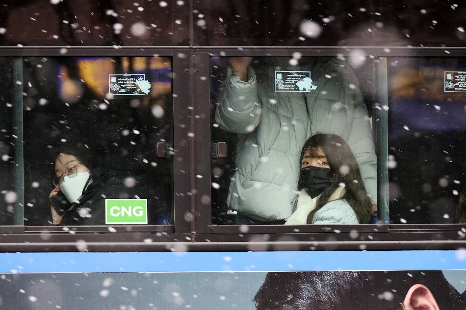 People sit inside a bus during snowfall, amid the coronavirus disease (COVID-19) pandemic, in central Seoul, South Korea, January 17, 2022. Kim Hong-Ji/ TPX IMAGES OF THE DAY, Reuters