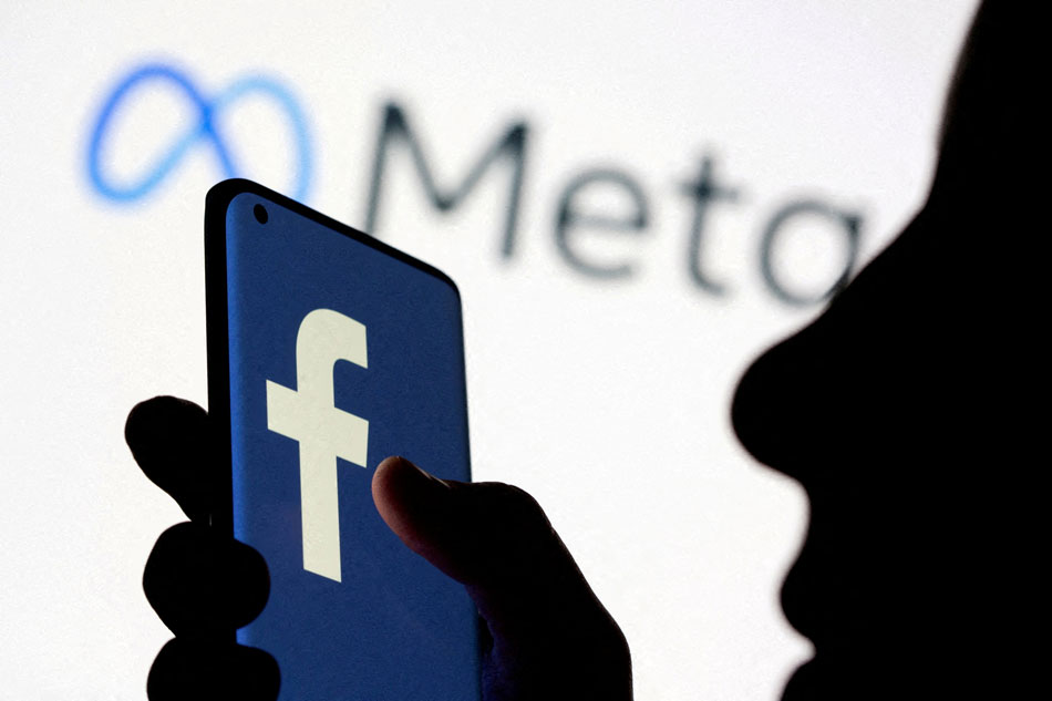  A woman holds smartphone with Facebook logo in front of a displayed Facebook's new rebrand logo Meta in this illustration picture taken October 28, 2021. Dado Ruvic, Reuters/Illustration/File Photo