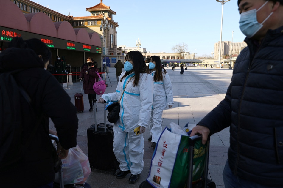 Travellers wearing personal protective equipment to prevent the spread of the coronavirus disease (COVID-19), line up to enter a railway station, ahead of the Chinese Lunar New Year holiday in Beijing, China January 28, 2022. Tingshu Wang, Reuters
