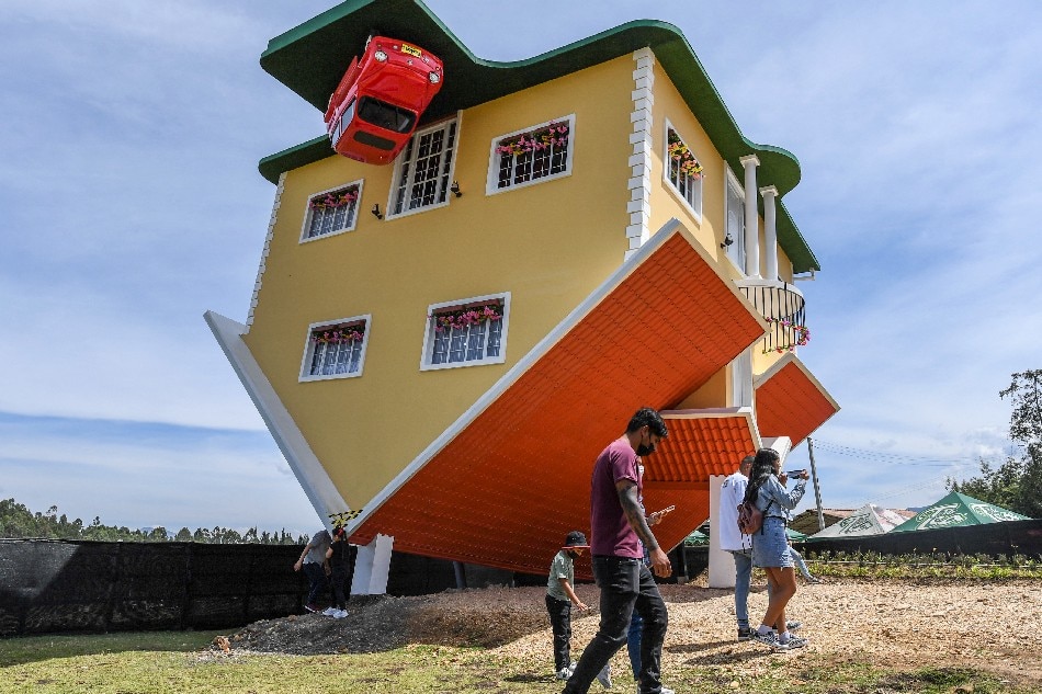 People walk outside the upside-down house, in Guatavita, near Bogota, on January 29, 2022. The house was designed by its Austrian owner Fritz Schall. Juan Barreto, Agence France-Presse