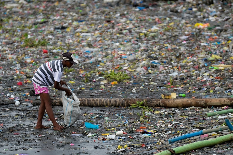 A woman picks up plastic cups along the riverbank of Pasig river, in Manila, June 10, 2021. Lisa Marie David, Reuters/file