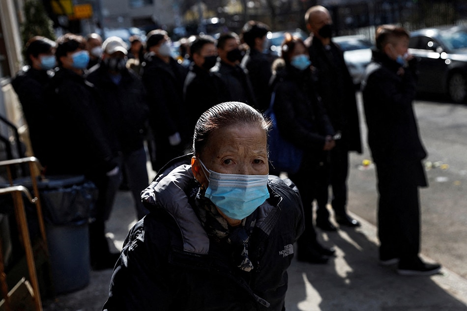 A woman wearing a protective face mask, amid the COVID-19 pandemic, walks during a funeral procession in the Chinatown section of the Manhattan borough of New York City, February 10, 2022. Shannon Stapleton, Reuters