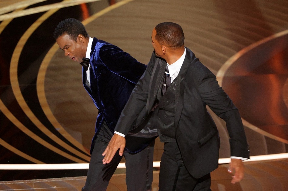 Will Smith (R) hits Chris Rock as Rock spoke on stage during the 94th Academy Awards in Hollywood, Los Angeles, California, U.S., March 27, 2022. Reuters/Brian Snyder