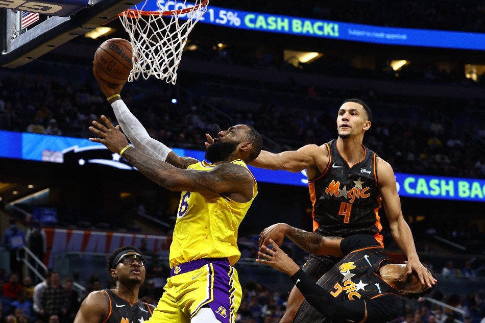 Lakers forward LeBron James shoots, as Orlando teammates Jalen Suggs and Chuma Okeke defend in their game January 21, 2022. Kim Klement, USA Today Sports/Reuters