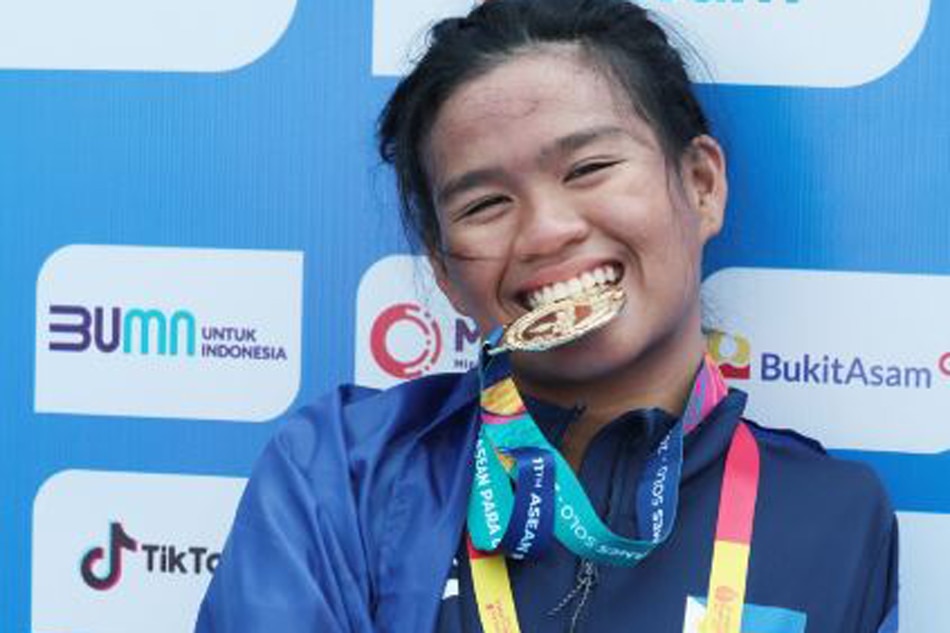 Rookie Angel Otom takes a bite at her gold medal after winning the women’s 50-meter butterfly S5 event on the way to emerging as the country’s first triple gold medalist in the 11th ASEAN Para Games at the Jatadiri Sports Complex pool in Semarang, Indonesia yesterday.