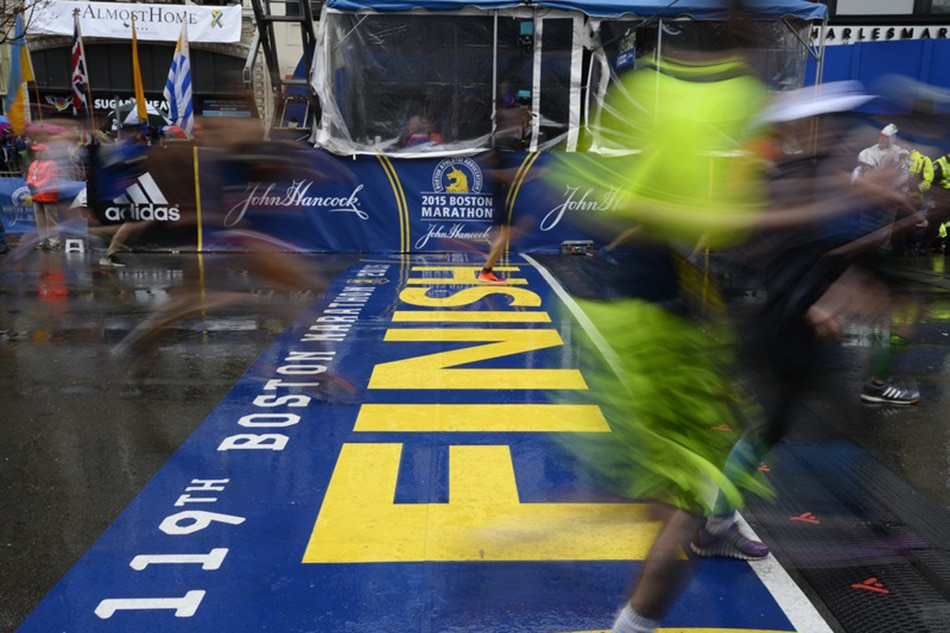Runners cross the finish line of the Boston Marathon on April 20, 2015.