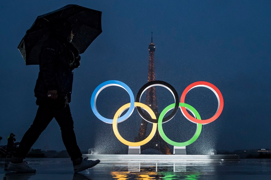 A passerby walks in front of the Olympic rings during a ceremony near the Eiffel Tower (seen rear) to celebrate the announcement of Paris' victorious 2024 Olympic bid, September 13, 2017. Ian Langsdon, EPA-EFE/file