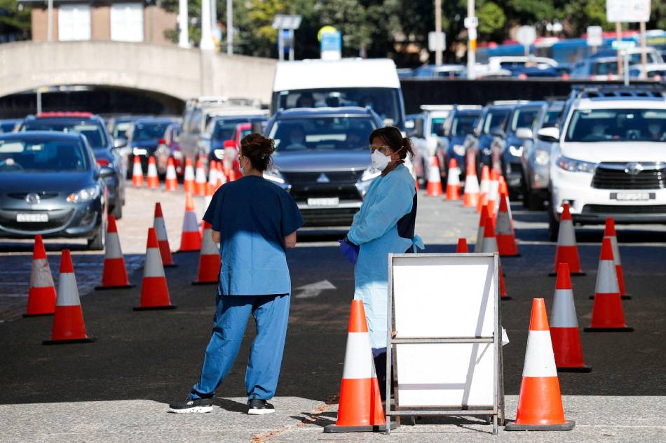 Health-care workers wait for the next vehicle at COVID-19 testing clinic as the omicron coronavirus variant continues to spread in Sydney, Australia, Dec. 30, 2021. Nikki Short, Reuters