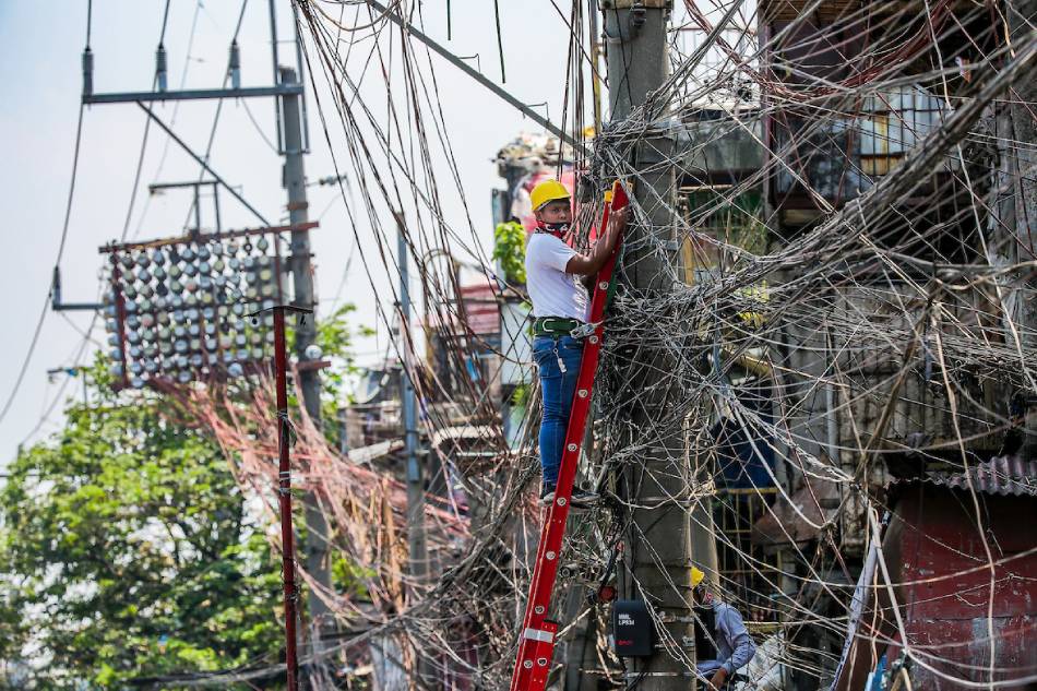  A lineman works on an electric post at the Katuparan housing project in Vitas, Tondo Manila on July 7, 2021. George Calvelo, ABS-CBN News