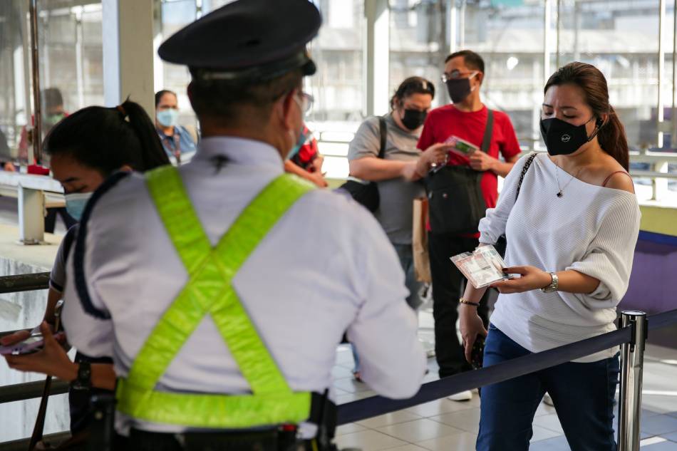 Security guards inspect vaccination cards and IDs of passengers entering LRT1’s Doroteo Jose Station in Manila on Jan. 18, 2022. George Calvelo, ABS-CBN News