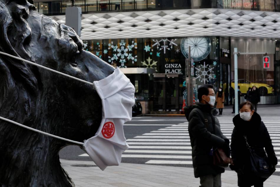 Pedestrians wearing protective masks, amid the coronavirus disease (COVID-19) outbreak, walk past a lion statue wearing a mask at a shopping district in Tokyo, Japan, January 26, 2022. REUTERS/Kim Kyung-Hoon/file
