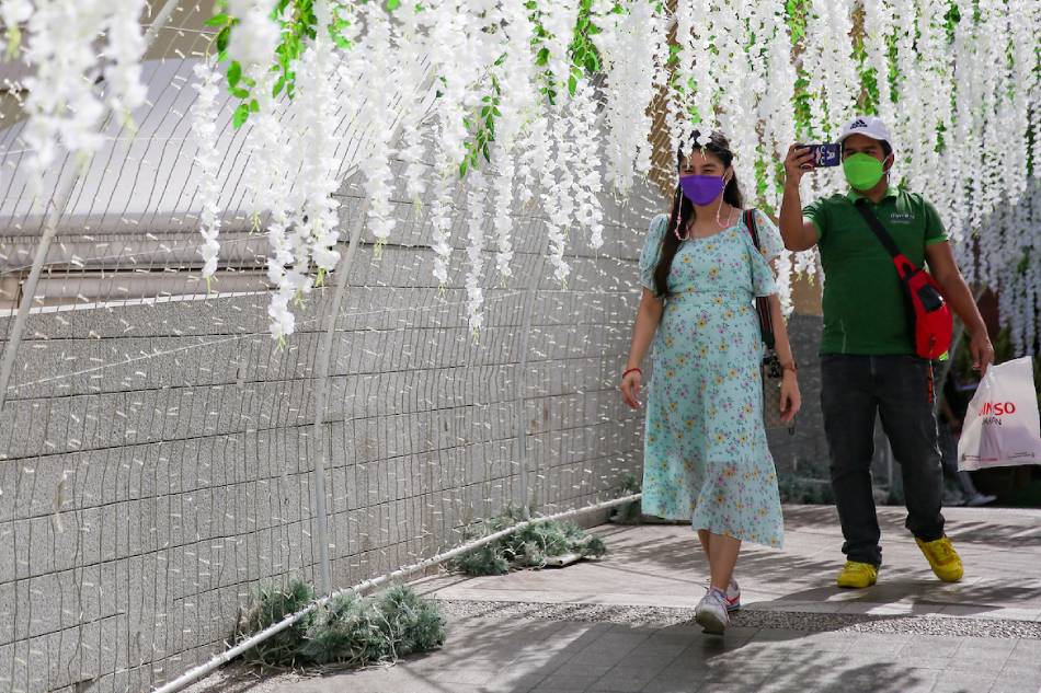 People stop by to take pictures at the Flower Tunnel installation at the Venice Grand Canal Mall in Taguig City on Feb. 12, 2022. Various decors and Valentine’s themed installations can be found in different malls in Metro Manila as people prepare to celebrate Valentine’s Day. George Calvelo, ABS-CBN News