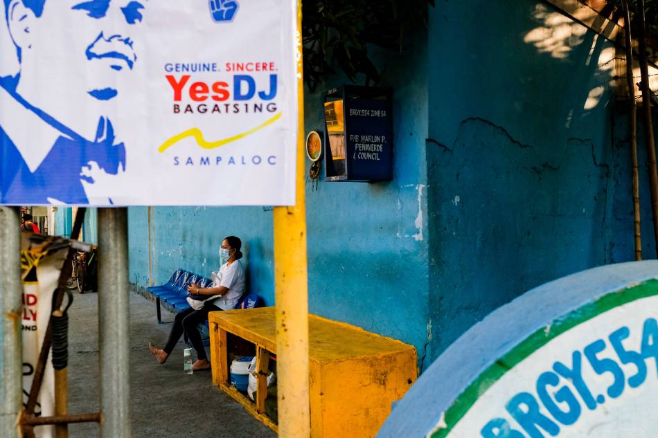 People pass by campaign posters near a bridge in Sampaloc, Manila on February 16, 2022. The Commission on Elections (COMELEC) drew flak today after videos of its enforcers dismantling campaign materials in private properties went viral on social media. George Calvelo, ABS-CBN News/FIle