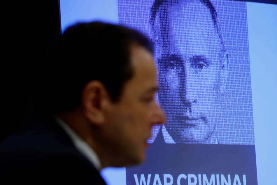 Russian President Vladimir Putin’s image is displayed on a screen next to the Ukraine’s ambassador to Japan Sergiy Korsunsky during a news conference in Tokyo, Japan, Feb. 25, 2022. Kim Kyung-Hoon, Reuters