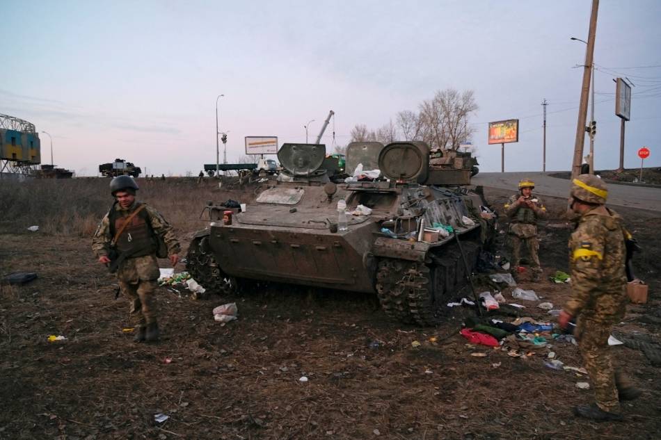 Ukrainian servicemen are seen next to a destroyed armored vehicle, which they said belongs to the Russian army, outside Kharkiv, Ukraine February 24, 2022. Maksim Levin, Reuters