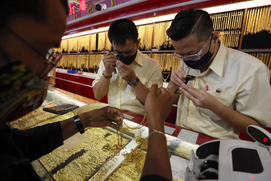 Thai goldsmiths examine gold ornaments sold by a customer during a trade at a gold shop in Chinatown, Bangkok, Thailand, 20 July 2020. Rungroj Yongrit, EPA-EFE/File