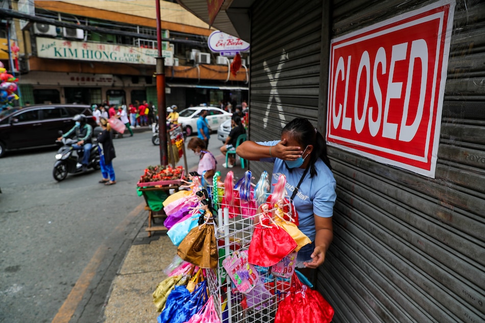 People pass by closed shops, some of which were affected by the ongoing COVID-19 pandemic, in Binondo, Manila during Chinese New Year on February 1, 2022. Jonathan Cellona, ABS-CBN News