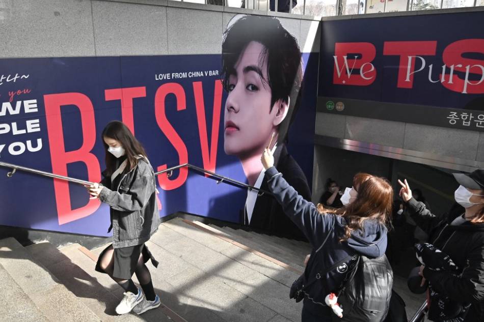 People take pictures in front of a big photo of V, a member of K-pop group BTS, at a subway station near Jamsil Olympic Stadium in Seoul, ahead of the group's live concert at the stadium. Jung Yeon-je, AFP