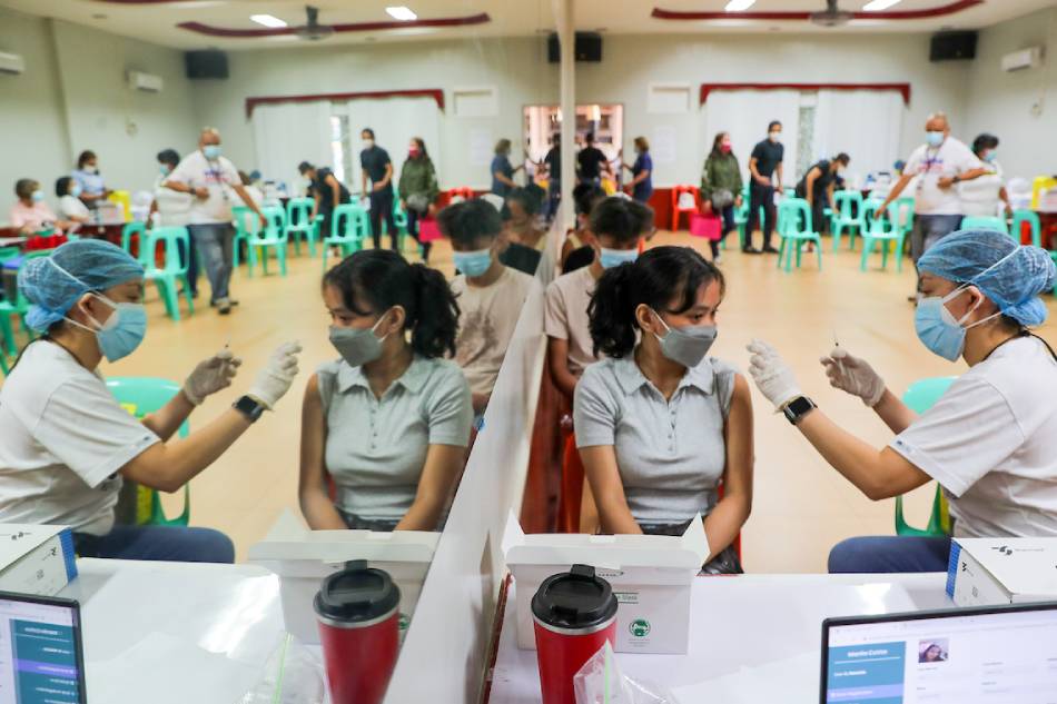 Members of the Manila Health Department inoculate residents against COVID-19 at the Ramon Magsaysay High School in Manila on Jan. 25, 2022 as the city opens up booster shots for walk-in non-residents working within its borders. Jonathan Cellona, ABS-CBN News/File