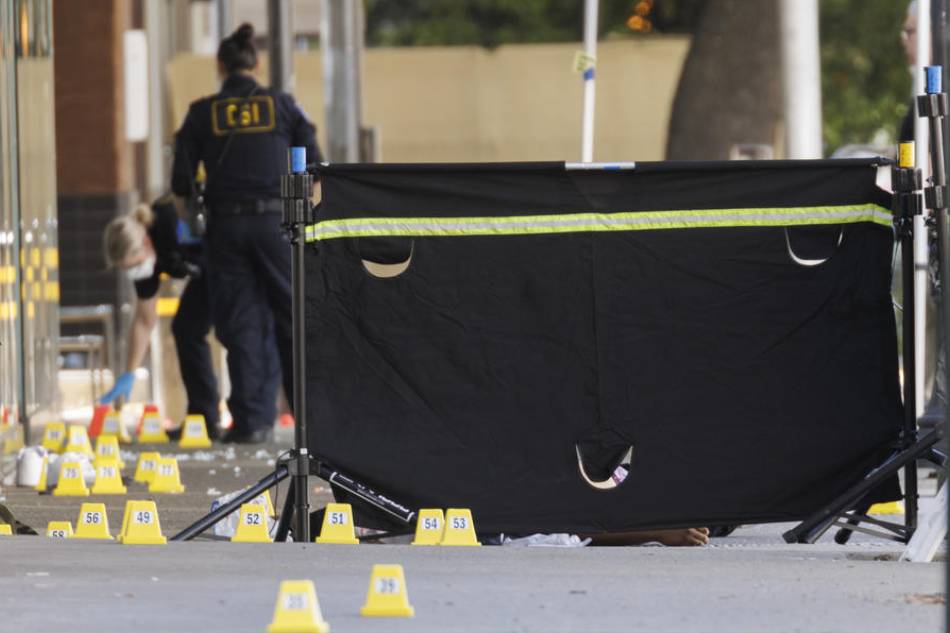 A barrier blocks the view of one of the victims as police officials mark evidence at the scene after a mass shooting in downtown Sacramento, California, USA, April 3, 2022. According the Sacramento Police Department, at least 6 people have been killed and more than 10 more injured in a gunfire in the city center on Sunday morning. Peter Dasiva, EPA-EFE 