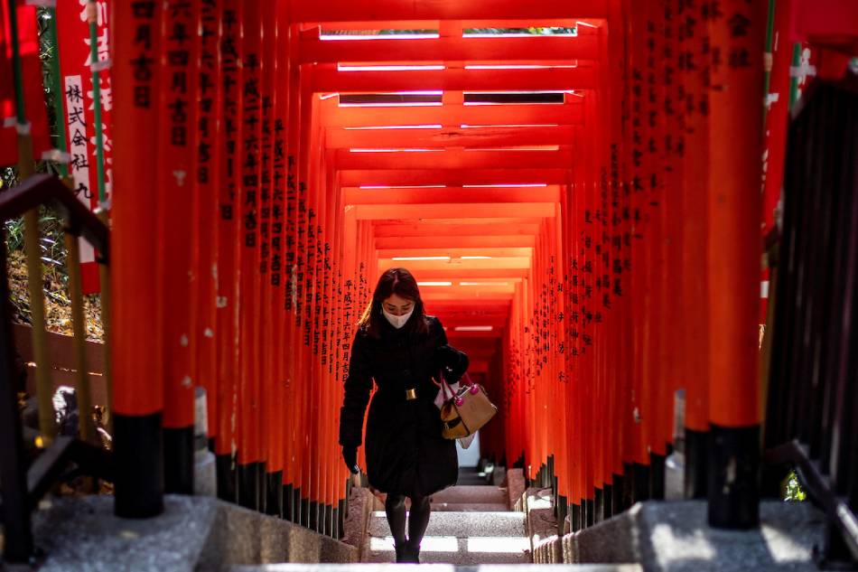 A woman wearing a face mask walks under a row of gates at Hie Shrine in Tokyo, Japan on Jan. 7, 2021 amid the COVID-19 pandemic. Philip Fong, AFP/File