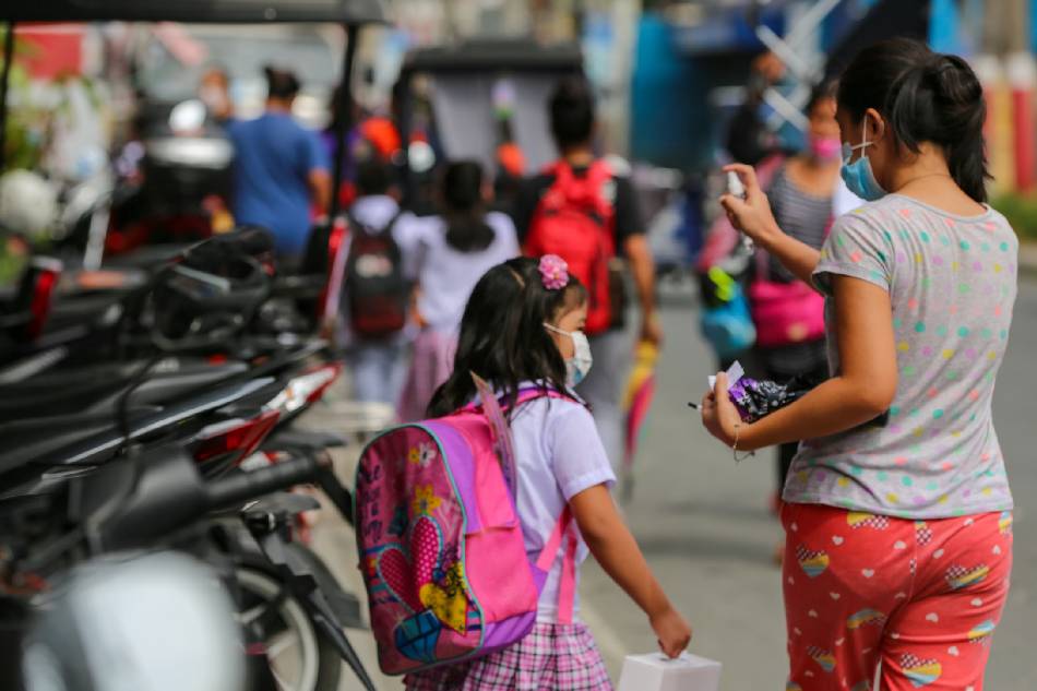 A mother sanitizes her child after attending the first day of face to face classes at the Ricardo P. Cruz Sr. Elementary School in Taguig City on Dec. 6, 2021. Jonathan Cellona, ABS-CBN News/File