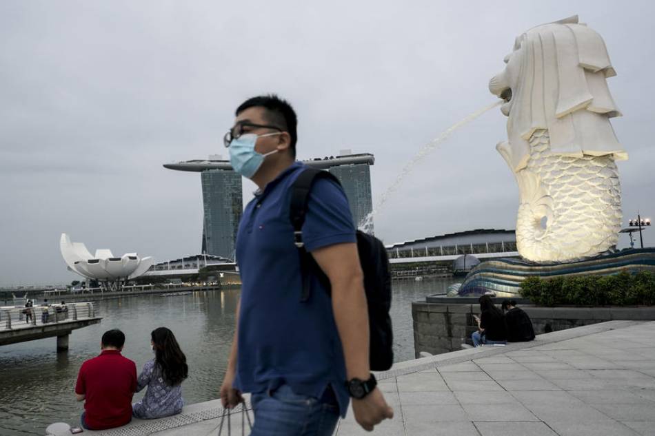 A man walks past the Marina Bay Sands hotel and the Merlion statue in Singapore, 14 July 2021. Wallace Woon, EPA-EFE/File