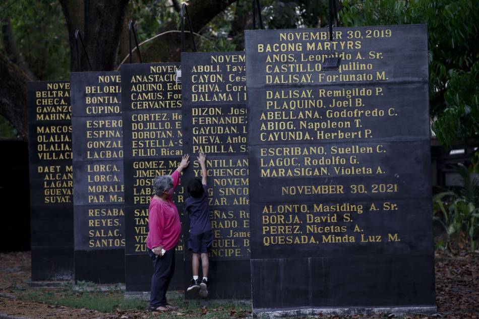 A citizen shows her grandson around the Bantayog ng mga Bayani (Monument of Heroes), which honors victims of human rights violations during the martial law years, during a cultural night for women's rights groups and remembrance of Martial Law victims in Quezon City, April 2, 2022. Activists have voiced concern over the possible return of 'a powerful dynasty' to the head of state and martial law era human rights abuses as Ferdinand 'Bongbong' Marcos Jr. led the polls in the run for the presidency in the May 9 elections